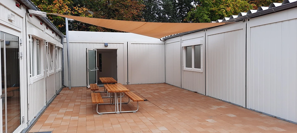 Unter unserem gro&szlig;en Sonnensegel stehen die neuen Sitzb&auml;nke auf dem Innenhof.