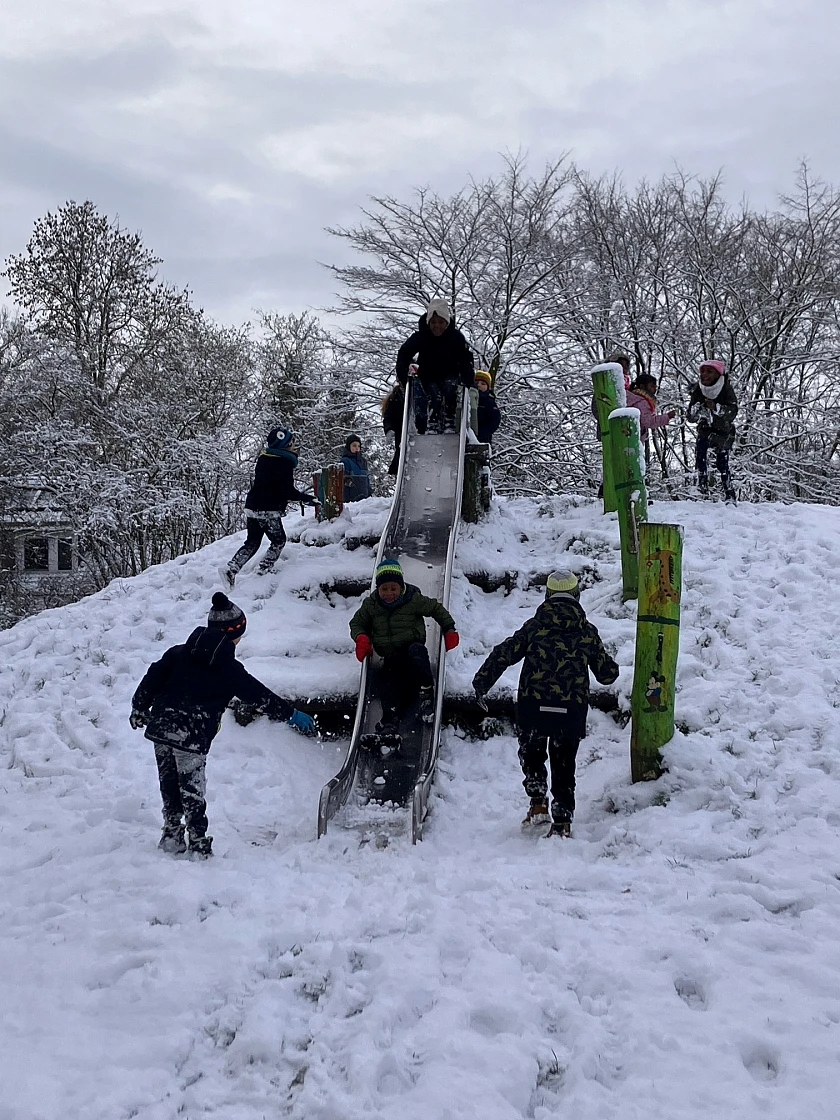 Kinder an der Rutsche auf dem verschneiten Spielplatz 